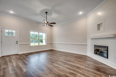 Unfurnished living room with ornamental molding, baseboards, ceiling fan, a fireplace, and wood finished floors