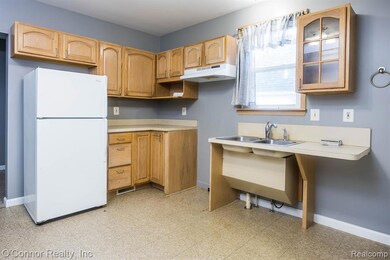 Kitchen with freestanding refrigerator, light floors, light countertops, and glass insert cabinets