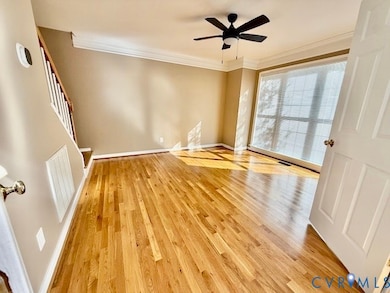 Spare room featuring crown molding, light wood finished floors, and ceiling fan