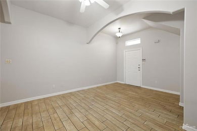 Entrance foyer featuring light wood-style floors, a ceiling fan, arched walkways, and lofted ceiling