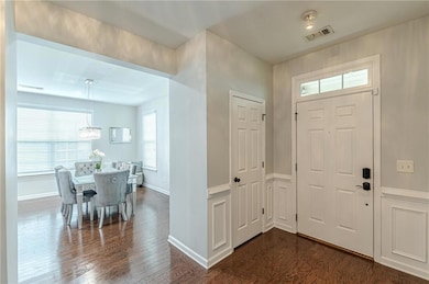 Entrance foyer featuring a chandelier, dark wood-style flooring, and baseboards