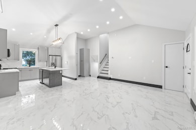 Kitchen with a center island, light marble finish floors, a breakfast bar, gray cabinetry, and open floor plan