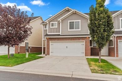 View of front of house with board and batten siding, driveway, brick siding, and a front lawn