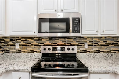 Kitchen with white cabinets, backsplash, stainless