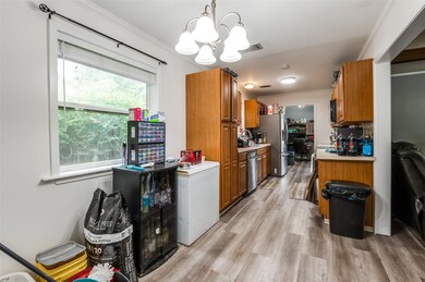 Kitchen with light hardwood / wood-style floors, an inviting chandelier, appliances with stainless steel finishes, decorative light fixtures, and crown molding