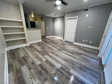 Unfurnished living room featuring a ceiling fan, ornamental molding, wood finished floors, and baseboards