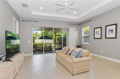 Living room with light tile patterned floors, a ceiling fan, recessed lighting, a raised ceiling, and baseboards