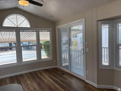 Entryway featuring a textured ceiling, vaulted ceiling, wood finished floors, and ceiling fan