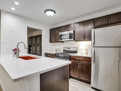 Kitchen with light countertops, dark brown cabine