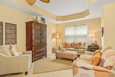 Living area with light tile patterned floors, a ceiling fan, and a raised ceiling