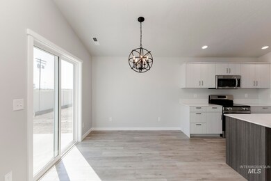 Kitchen with stainless steel appliances, white cabinetry, a chandelier, decorative light fixtures, and light wood-type flooring