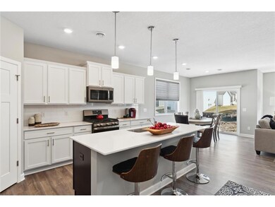 One-level living with dream kitchen featuring an oversized island, quartz countertops, tile backsplash, slate finish appliance package including refrigerator and walk-in pantry. Photo of model home, colors and finishes will vary.