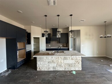 Kitchen with tasteful backsplash, a kitchen island with sink, a breakfast bar area, wall chimney exhaust hood, and hanging light fixtures