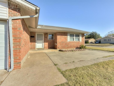 Doorway to property featuring covered porch, brick siding, roof with shingles, and a yard