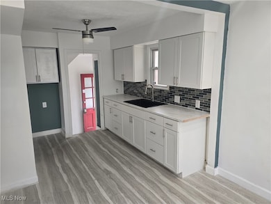 Kitchen featuring white cabinets, light wood-style flooring, backsplash, healthy amount of natural light, and a textured ceiling