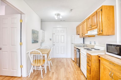 Kitchen with white appliances, light hardwood / wo