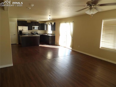 Kitchen with open floor plan, dark wood-style flooring, a chandelier, and a textured ceiling