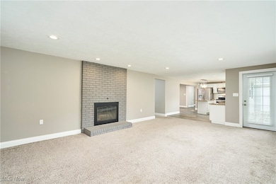 Unfurnished living room featuring light colored carpet, a fireplace, and recessed lighting