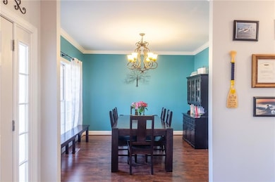 Dining room featuring dark wood-style floors, a notable chandelier, ornamental molding, and baseboards