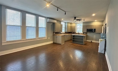 Kitchen with gray cabinetry, ceiling fan, dark woo