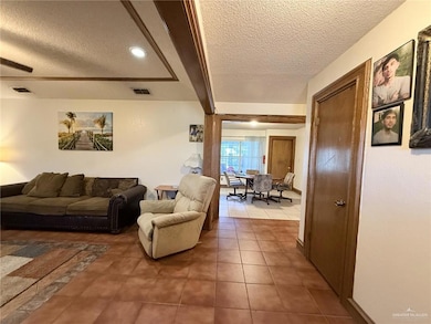 Living area featuring a textured ceiling, beam ceiling, and tile patterned floors