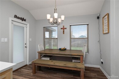Dining room featuring dark hardwood / wood-style flooring, lofted ceiling, and a chandelier