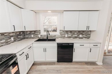 Kitchen featuring black appliances, white cabinets, light wood-type flooring, and light stone counters