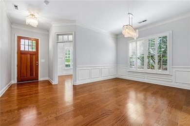 Foyer entrance with a chandelier, ornamental molding, and wood finished floors