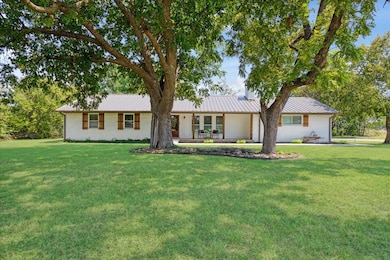 Ranch-style house with a front yard, covered porch, and a metal roof