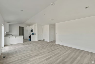 Unfurnished living room with vaulted ceiling and light wood-style floors