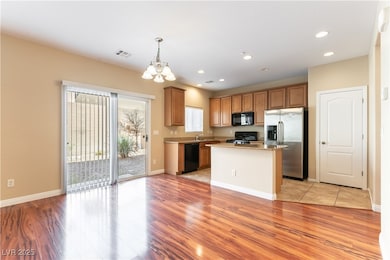 Kitchen with black appliances, a chandelier, light