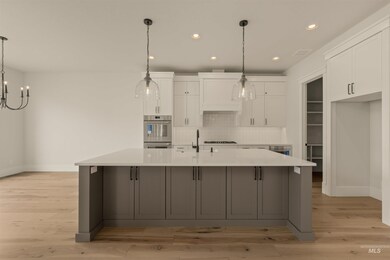 Kitchen with white cabinetry, hanging light fixtures, tasteful backsplash, a spacious island, and gray cabinetry
