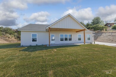 Front view of property featuring a lawn, a patio, and board and batten siding