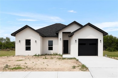 View of front facade featuring a garage, driveway, stucco siding, and a shingled roof