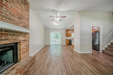 Unfurnished living room featuring ceiling fan, wood finished floors, stairs, a fireplace, and beamed ceiling
