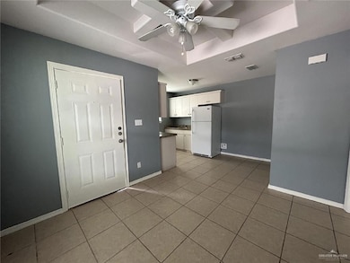 Kitchen featuring freestanding refrigerator, a tray ceiling, white cabinetry, and light tile patterned floors