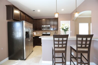 The kitchen with bar seating, an arched entry to the main living area, and stainless appliances.