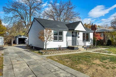 View of front of home featuring an outdoor structure, a shingled roof, a detached garage, driveway, and a front lawn