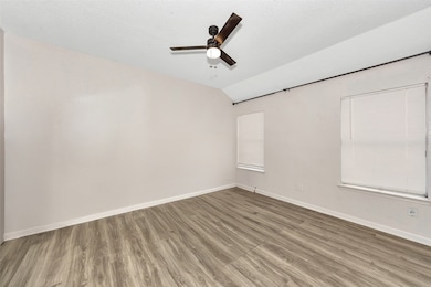 Unfurnished room featuring wood finished floors, lofted ceiling, a textured ceiling, and ceiling fan