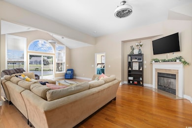 Living room featuring vaulted ceiling, baseboards, a fireplace with flush hearth, and wood finished floors