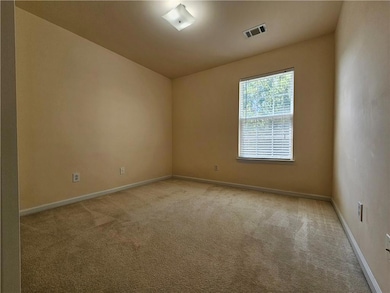 Empty room with light colored carpet and baseboards