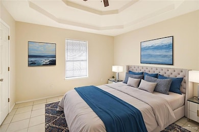 Bedroom featuring light tile patterned floors, a tray ceiling, and ceiling fan