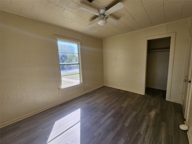 Unfurnished bedroom featuring ceiling fan, dark hardwood / wood-style flooring, and a closet
