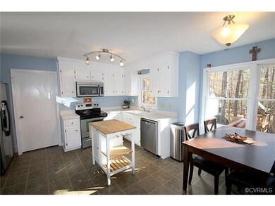 Open eat-in kitchen features white cabinetry, stai