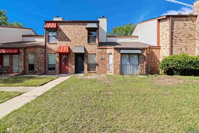 Exterior space featuring brick siding, french doors, a chimney, and a front lawn