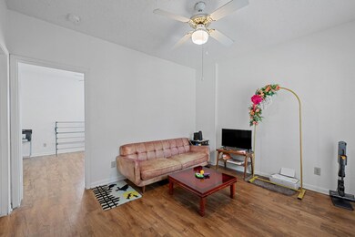 Living room with ceiling fan, wood finished floors, and a textured ceiling