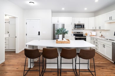 The open-concept kitchen serves as the heart of the home, featuring a spacious center island with stunning quartz countertops, perfect for meal preparation, casual dining, or entertaining guests.