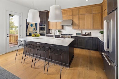 Kitchen featuring stainless steel appliances, a kitchen breakfast bar, recessed lighting, a large center island, and door leading to back deck. Photo is representative of the Acworth Model Home. Designer features will vary.
