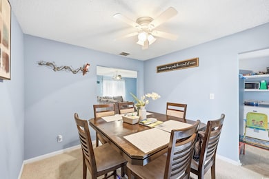 Dining room featuring light colored carpet, a textured ceiling, and ceiling fan