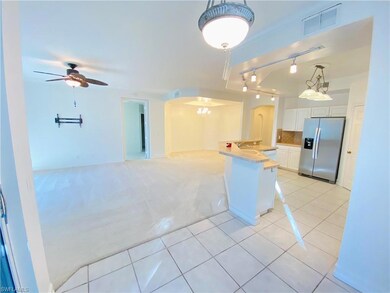 Kitchen with light tile patterned floors, open floor plan, rail lighting, light colored carpet, and stainless steel fridge with ice dispenser
